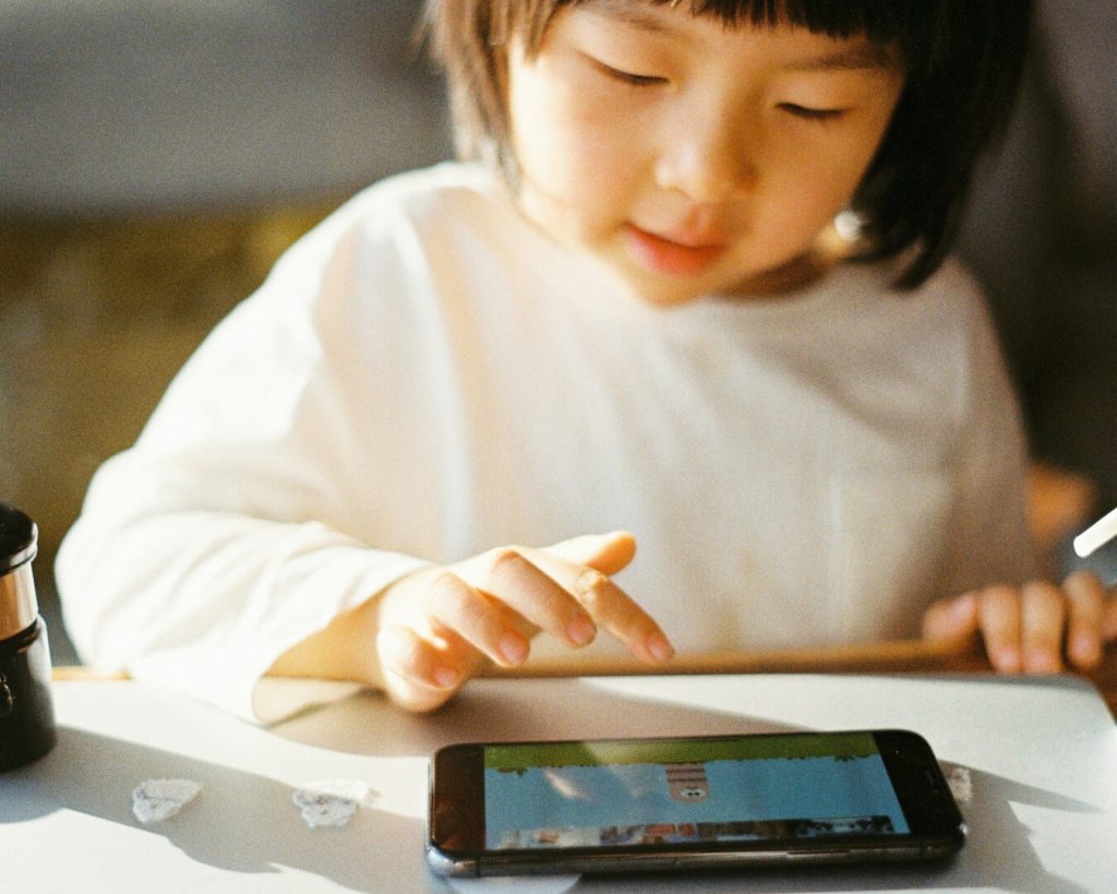 Una bambina intenta a giocare con il cellulare